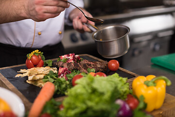 Image showing Chef hand finishing steak meat plate