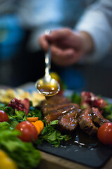 Image showing Chef hand finishing steak meat plate