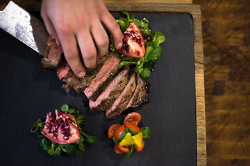 Image showing top view of Chef hands serving beef steak