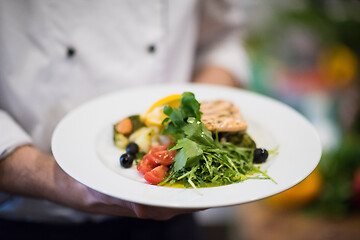 Image showing Chef hands holding dish of fried Salmon fish fillet