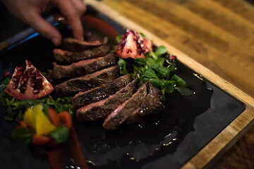 Image showing closeup of Chef hands serving beef steak