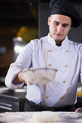 Image showing chef sprinkling flour over fresh pizza dough