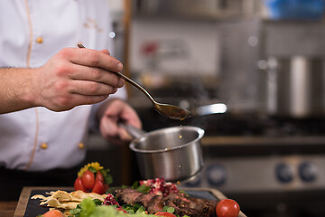 Image showing Chef hand finishing steak meat plate