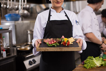 Image showing female Chef holding beef steak plate