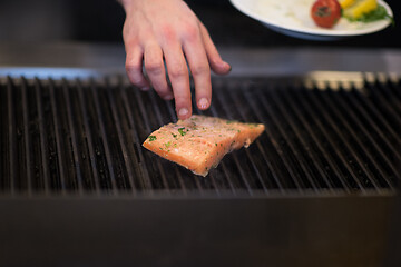 Image showing chef hands cooking grilled salmon fish