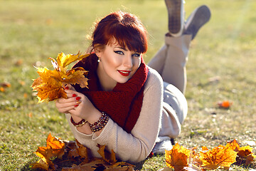 Image showing Girl lying on ground with yellow leaves