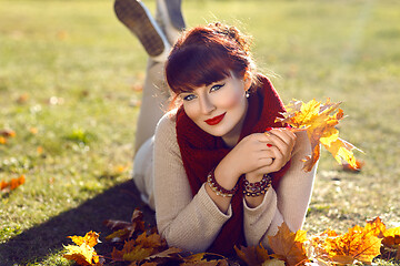 Image showing Girl lying on ground with yellow leaves