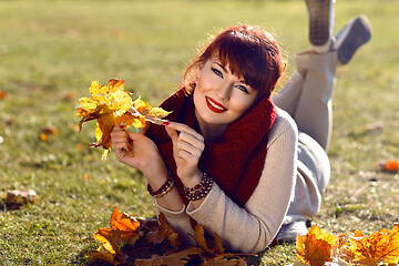 Image showing Girl lying on ground with yellow leaves