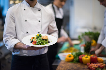 Image showing Chef hands holding dish of fried Salmon fish fillet