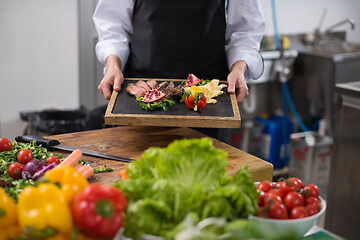 Image showing female Chef holding beef steak plate