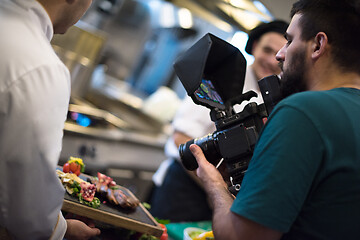 Image showing videographer recording while team cooks and chefs preparing meal