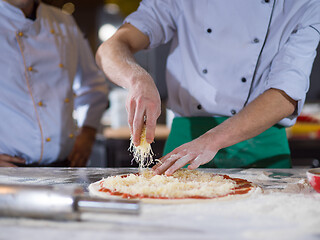 Image showing chef sprinkling cheese over fresh pizza dough