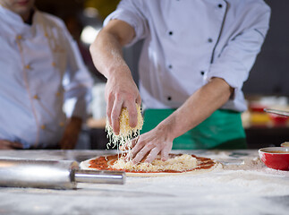 Image showing chef sprinkling cheese over fresh pizza dough