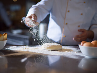 Image showing chef sprinkling flour over fresh pizza dough