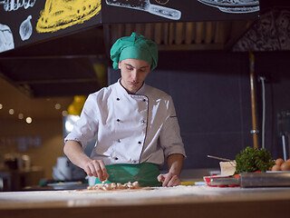 Image showing chef putting fresh mushrooms on pizza dough