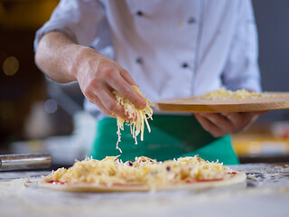 Image showing chef sprinkling cheese over fresh pizza dough