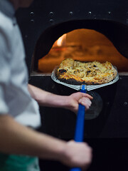 Image showing chef removing hot pizza from stove