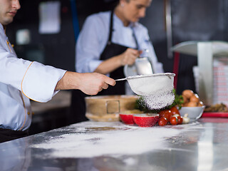 Image showing chef sprinkling flour over fresh pizza dough