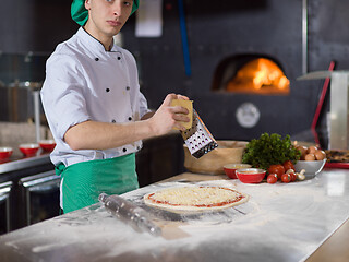 Image showing chef sprinkling cheese over fresh pizza dough