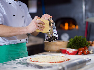 Image showing chef sprinkling cheese over fresh pizza dough