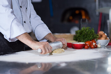 Image showing chef preparing dough for pizza with rolling pin