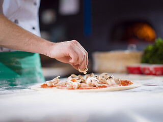 Image showing chef putting fresh mushrooms on pizza dough