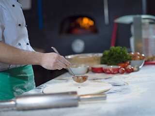 Image showing chef putting cut sausage or ham on pizza dough