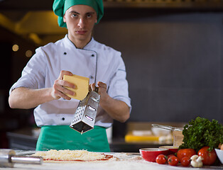 Image showing chef sprinkling cheese over fresh pizza dough