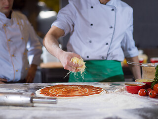 Image showing chef sprinkling cheese over fresh pizza dough