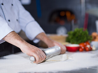 Image showing chef preparing dough for pizza with rolling pin