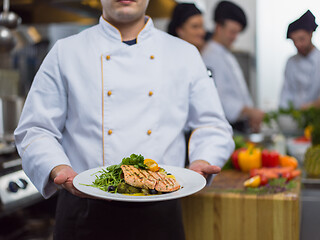 Image showing Chef holding dish of fried Salmon fish fillet