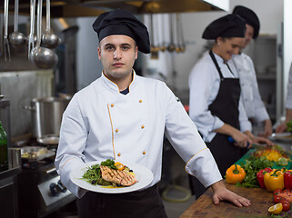 Image showing Chef holding dish of fried Salmon fish fillet