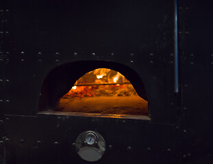 Image showing chef putting delicious pizza to brick wood oven