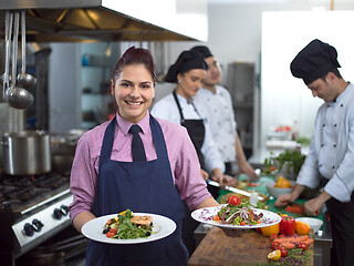 Image showing young waitress showing dishes of tasty meals