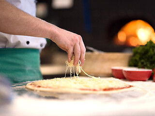 Image showing chef sprinkling cheese over fresh pizza dough