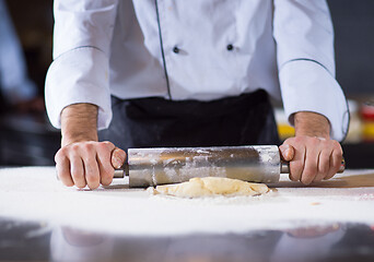 Image showing chef preparing dough for pizza with rolling pin