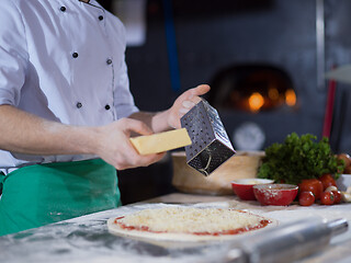 Image showing chef sprinkling cheese over fresh pizza dough