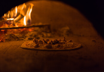 Image showing chef putting delicious pizza to brick wood oven