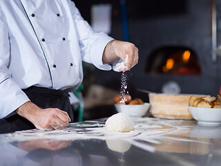 Image showing chef sprinkling flour over fresh pizza dough