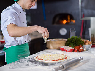 Image showing chef sprinkling cheese over fresh pizza dough
