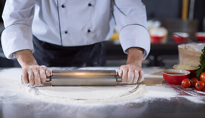 Image showing chef preparing dough for pizza with rolling pin