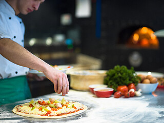 Image showing chef putting fresh vegetables on pizza dough