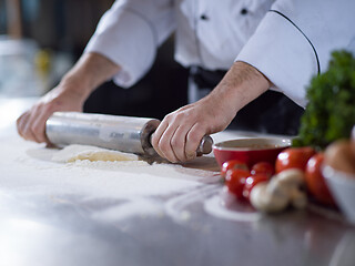 Image showing chef preparing dough for pizza with rolling pin