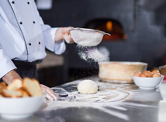 Image showing chef sprinkling flour over fresh pizza dough