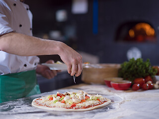 Image showing chef putting fresh vegetables on pizza dough