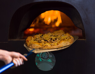 Image showing chef removing hot pizza from stove