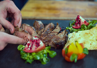 Image showing closeup of Chef hands serving beef steak