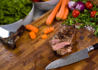 Image showing Juicy slices of grilled steak on wooden board