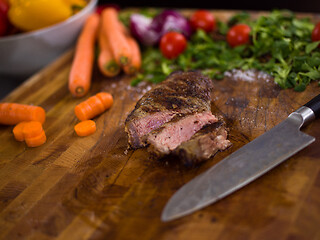 Image showing Juicy slices of grilled steak on wooden board