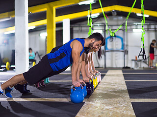 Image showing young athletes doing pushups with kettlebells